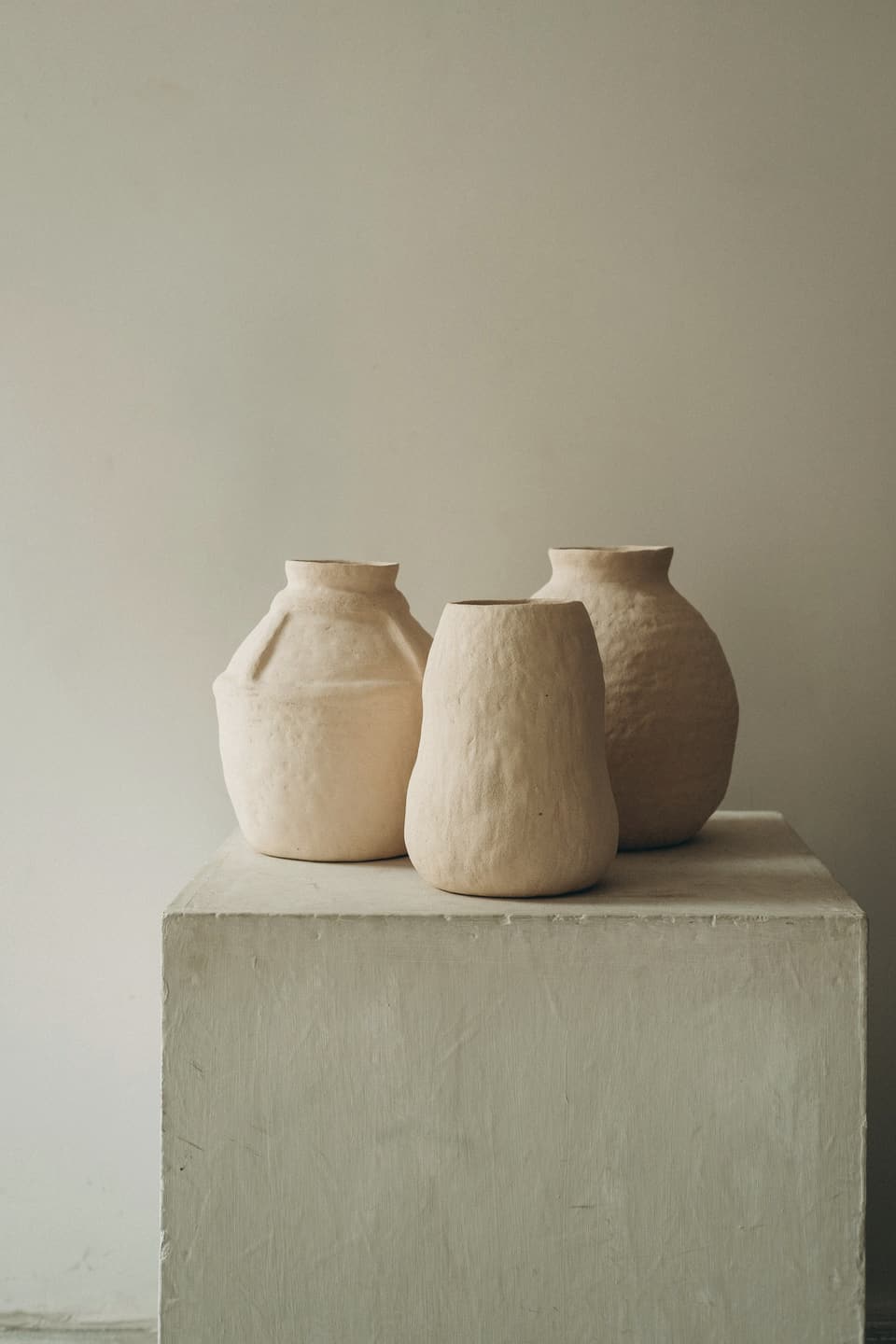 Three hand-thrown oat stoneware vases on a plaster plinth
