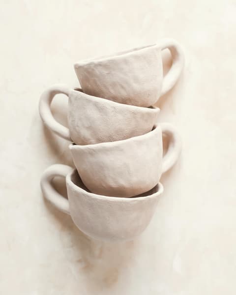 Three blush-pink cups stacked on a linen surface