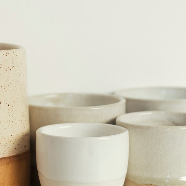 Stoneware cups with a sand-coloured base and white rim, detail of the glaze