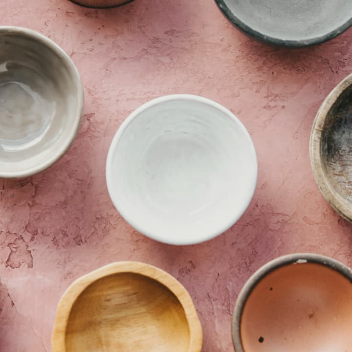 Nine small bowls in ochre, grey, white and pink glazes seen from above, detail of the glaze