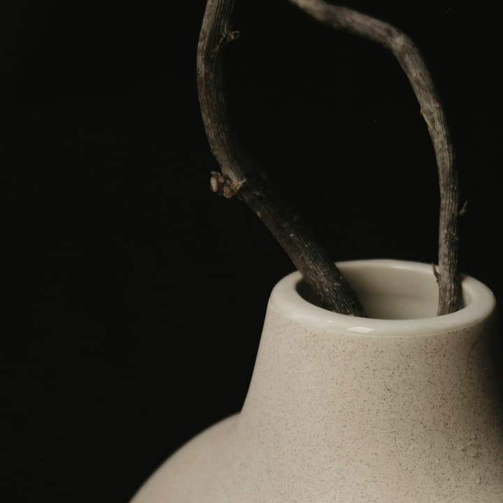 Close-up of a pale oat stoneware vase with a ridged surface, detail of the glaze