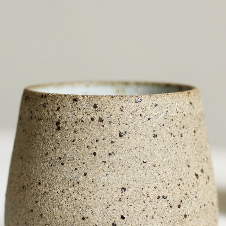 Speckled oat tumbler on a white plinth, detail of the glaze