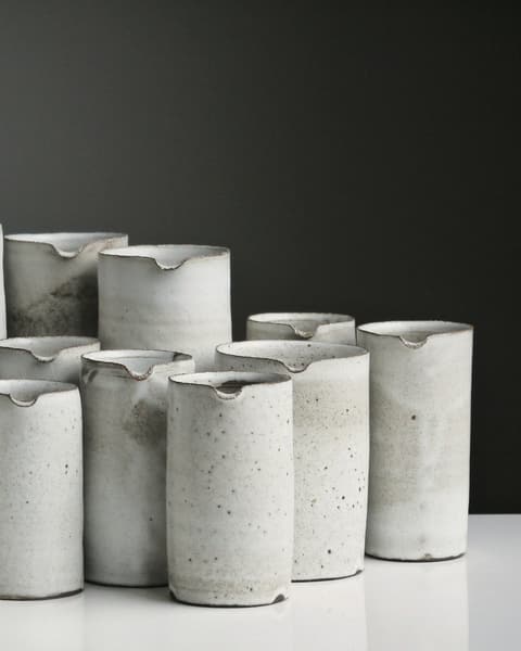 Six chalk-white stoneware tumblers grouped together