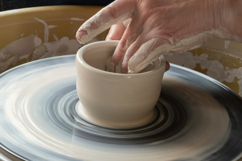 A bowl being thrown on a spinning wheel